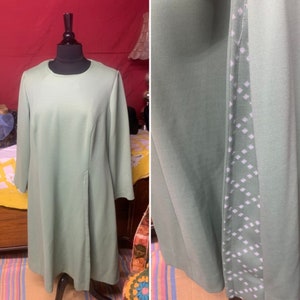 May include: A sage green dress with a white geometric pattern on the side seam. The dress has a round neckline and long sleeves.