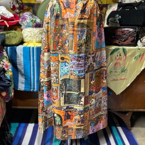 May include: A long, flowing skirt with a colorful, patterned design featuring a collage of images. The skirt is made of a lightweight fabric and has a gathered waist.
