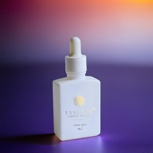May include: A white, square-shaped bottle with a dropper top. The bottle has gold text that reads "ESSENCE EMBODY DIVINE" and "SIDDIC DROPS". The background is a gradient of purple, orange, and yellow.
