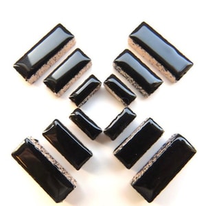 May include: A set of ten black ceramic tiles with a light brown border. The tiles are rectangular and vary in size.