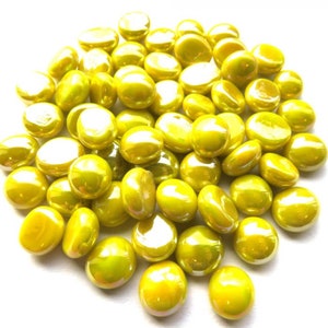 May include: A pile of yellow glass beads with a pearlescent finish. The beads are smooth and round, and they are perfect for adding a touch of sparkle to any craft project.