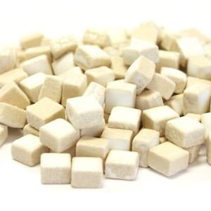 May include: A pile of small, off-white ceramic tiles. The tiles are square and have a slightly textured surface.
