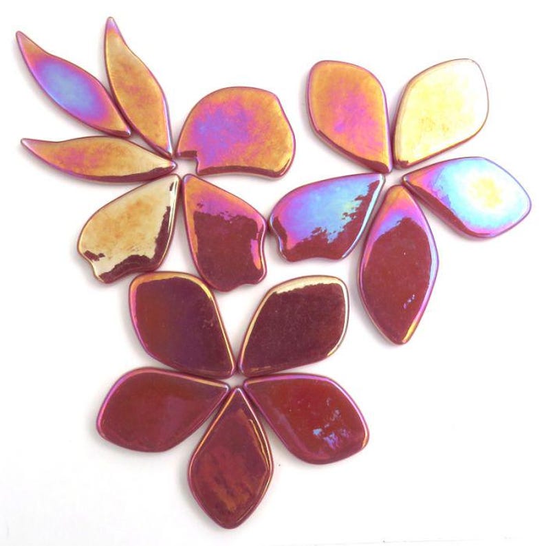 Pu&ograve; includere: Un set di petali di fiori in vetro iridescente in tonalit&agrave; di rosa, oro e viola. I petali sono disposti a grappolo, creando un motivo floreale.