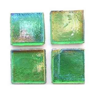 May include: Four square glass tiles with iridescent green and blue hues. The tiles have a textured surface and are arranged in a square formation. The glass appears to have a slight shimmer, reflecting various colors.