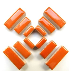 May include: Orange rectangular tiles with a glossy finish and a light beige border are arranged on a white surface. The tiles are in various orientations, showcasing their shape and color.