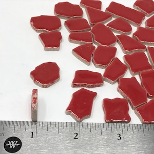 May include: Red ceramic mosaic tiles in various irregular shapes. The tiles have a glossy finish and a gray edge. A ruler shows the tiles are approximately 1 inch in length.
