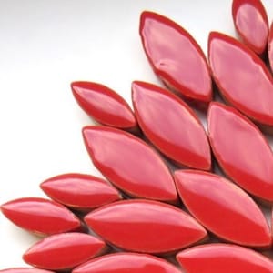 May include: A close-up of a collection of red ceramic tiles shaped like elongated leaves. The tiles are arranged in a fan shape, with the tips of the leaves pointing outwards.