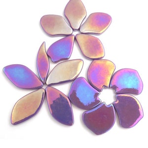Pu&ograve; includere: Un set di piastrelle in ceramica a forma di fiore di colore viola iridescente. Le piastrelle sono disposte a forma di fiore con cinque petali.