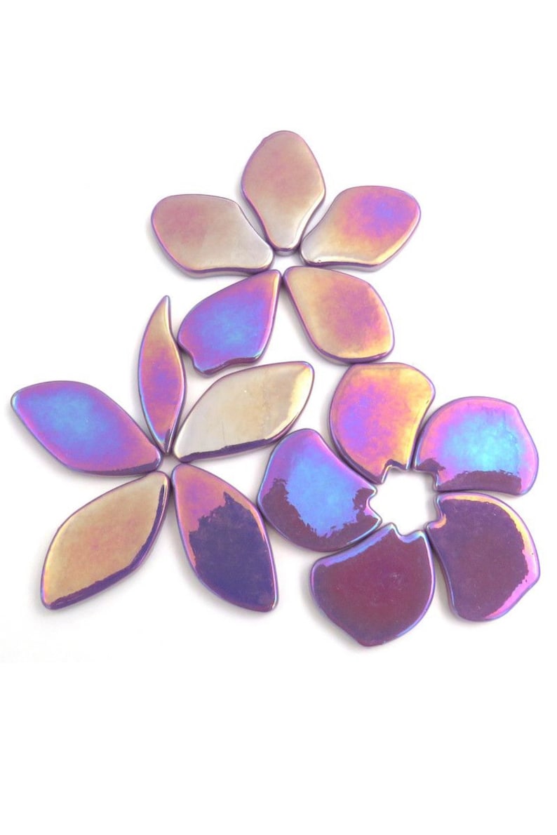 Pu&ograve; includere: Un set di piastrelle in ceramica a forma di fiore di colore viola iridescente. Le piastrelle sono disposte a forma di fiore con cinque petali.