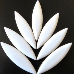 May include: A set of ten white ceramic tiles shaped like elongated leaves. The tiles are arranged in a symmetrical pattern, with the points of the leaves meeting in the center.