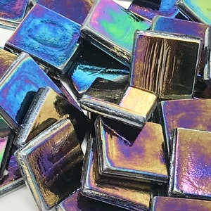 May include: A pile of iridescent black square glass tiles. The tiles have a metallic sheen and reflect different colors of the rainbow.