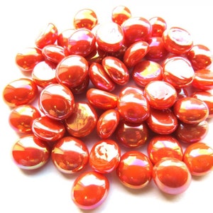 May include: A pile of iridescent orange glass pebbles. The pebbles are smooth and round, and they have a slight shimmer to them.