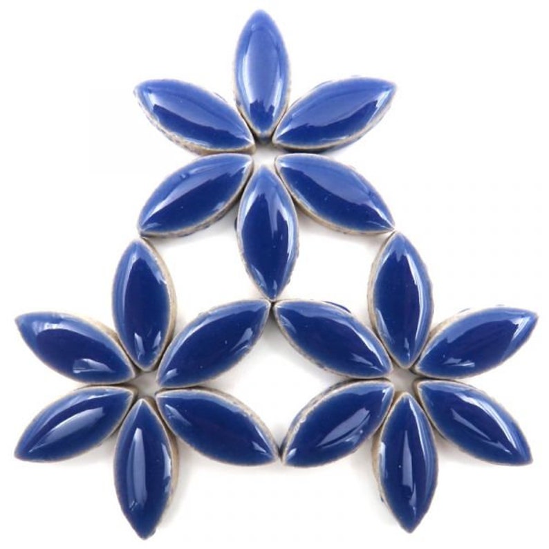 Op de afbeelding: Een groep blauwe, keramische tegels in de vorm van een bloem, gerangschikt in een symmetrisch patroon. De tegels zijn glanzend en hebben een licht verhoogd midden.