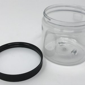 May include: A clear plastic jar with a black screw-on lid. The jar is empty and the lid is off.