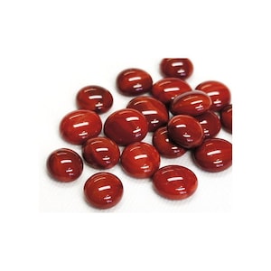 May include: A pile of red glass marbles, each with a slightly different shade of red and a glossy finish.