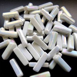 May include: A collection of iridescent white rectangular mosaic tiles. The tiles have a glossy finish and reflect a subtle rainbow sheen. These small, rectangular tiles are ideal for various craft and design projects.