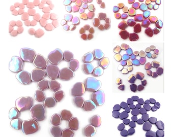 May include: Assortment of iridescent glass mosaic tiles in various shades of pink, purple, and blue. The tiles are shaped like irregular flowers with multiple petals.