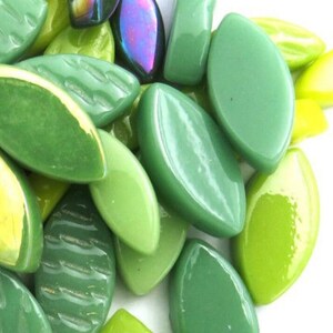 May include: A collection of green glass beads in various shades, including lime, olive, and emerald. Some beads have a leaf shape, while others are rectangular or oval. A few beads have an iridescent sheen.