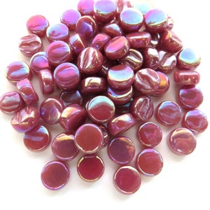 May include: A pile of iridescent, burgundy-colored glass mosaic tiles. The round, flat tiles have a glossy finish and reflect a rainbow of colors. These decorative tiles are ideal for craft projects.