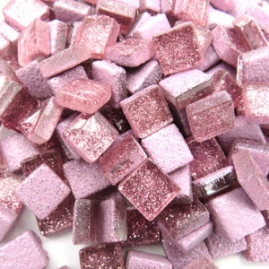 May include: A pile of small, square, pink glass tiles with a glittery finish. The tiles are perfect for crafting and home decor projects.