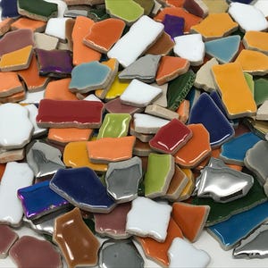 May include: A collection of colorful ceramic tile pieces in various shapes and sizes. The tiles are in shades of blue, green, red, orange, yellow, white, and silver.