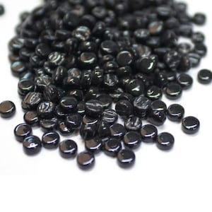 May include: A pile of black glass beads, each with a slightly different texture and sheen.