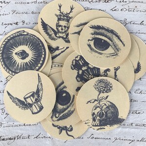 May include: A set of 10 round, beige paper stickers with black and white illustrations. The illustrations include a skull with wings, an eye, a flower growing from a skull, and a skull with a crown.
