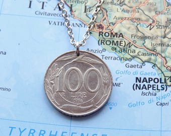 May include: A silver-toned metal coin pendant featuring the number 100 and the text 100 LIRE 1996, suspended from a silver-coloured metal chain. The coin displays an embossed design of wheat stalks and a dolphin, hanging over a map of Italy.