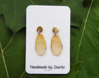 May include: Handmade petal earrings with gold-coloured studs. The earrings have a teardrop shape, with yellow and cream petals. The card reads "Handmade by Charlie est. 2014".