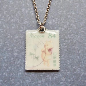 Winnie the Pooh guarda i fiori | Collana con francobollo postale giapponese | A.A. Milne | gioielli con francobolli | collezionista di francobolli postali | gioielli di libri | verme di libri