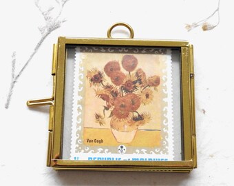 May include: A square brass frame with a hinged side latch and a top hanging loop, containing a postage stamp featuring a Van Gogh sunflower painting. The stamp displays the text Van Gogh and Republic of Maldives in a decorative border.