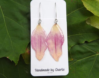 May include: Handmade earrings with pink and yellow flower petals set in clear resin, suspended from silver-tone hooks. The card behind the earrings reads "Handmade by Charlie EST. 2014."