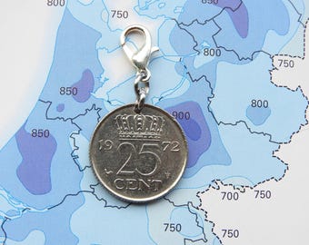 May include: A silver-toned metal charm featuring a circular 1972 Dutch 25 cent coin with a crown emblem above the number 25. The coin is attached to a silver-coloured lobster claw clasp, allowing it to be easily clipped onto various items.