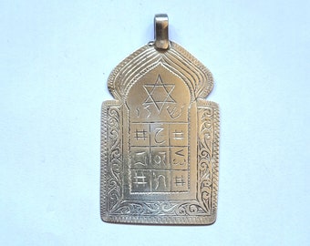 Pode incluir: Pingente de prata com um design ornamentado que apresenta uma estrela de David e caracteres hebraicos. O pingente tem a forma de um pequeno arco.