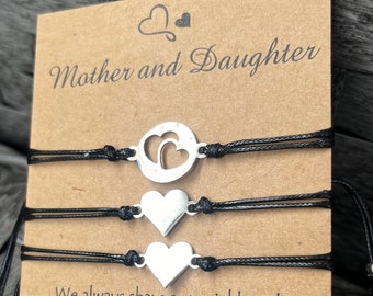 May include: Two black string bracelets with silver heart charms. The card reads "Mother and Daughter" and "We always share a special bond, though near or far apart, the words that would describe it, are written on the heart."