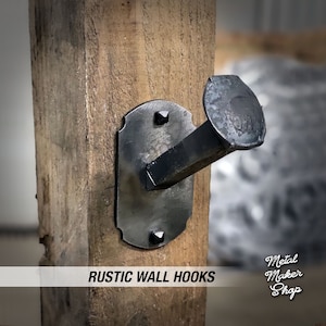 May include: A rustic wall hook made from a repurposed nail with a metal backing plate. The hook is mounted on a wooden post. The text "RUSTIC WALL HOOKS" is visible at the bottom of the image.