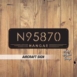 May include: Black metal sign with white lettering that reads "N95870 HANGAR" and the text "AIRCRAFT SIGN" below.
