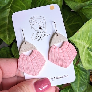 May include: A pair of pink and beige dangle earrings with a fringe design. The earrings are made of polymer clay and have a silver hook.