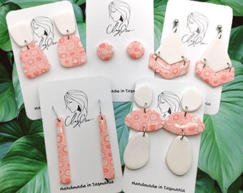 May include: Assortment of handmade ceramic earrings in pink and white with geometric patterns. The earrings are displayed on white cards with the text "Handmade in Tasmania".
