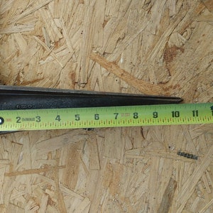 May include: A close-up of a metal tool with a yellow measuring tape. The tool is 13 inches long and has a black handle. The tool is on a wood surface.