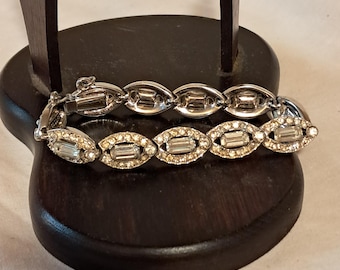 Pulseira vintage Bogoff prateada com strass transparentes e assinatura.