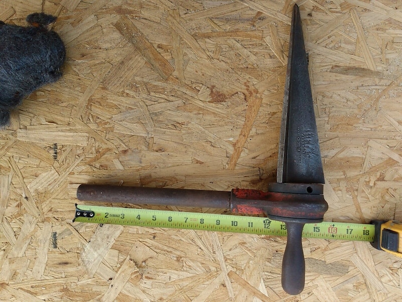 May include: A rusty metal pipe cutter with a red handle and a long, pointed blade. The cutter is 18 inches long.