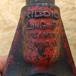 May include: A red and black pipe wrench with the text "RIDGID LONG GRIP MADE IN AMERICA NO. 3" on the side.