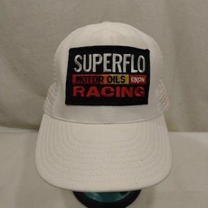 Könnte beinhalten: Weiße Mesh-Trucker-Kappe mit einem schwarzen Patch, auf dem "SUPERFLO MOTOR OILS EXXON RACING" in rot, gelb und weiß steht.
