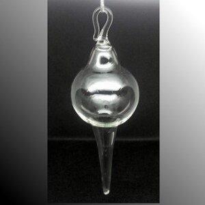May include: A clear glass ornament with a teardrop shape and a loop at the top for hanging.