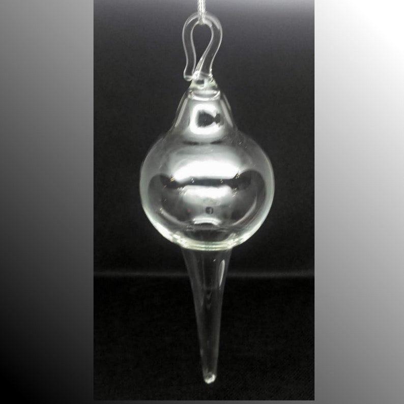 May include: A clear glass ornament with a teardrop shape and a loop at the top for hanging.