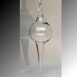 May include: A clear glass Christmas ornament with a pointed tip and a loop for hanging.