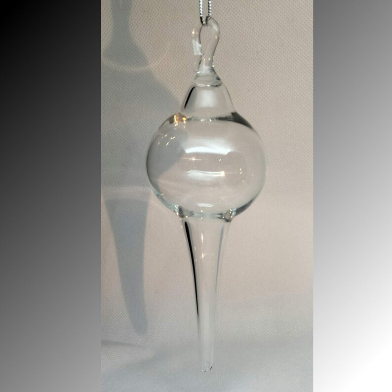 May include: A clear glass Christmas ornament with a pointed tip and a loop for hanging.
