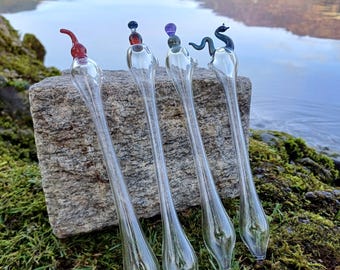 May include: Four glass blowing pipes with different colored glass accents. The pipes are clear glass with a bulbous end and a long, thin stem. The accents are a red, purple, blue, and a black dragon.