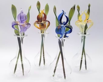 May include: Five glass vases with colorful glass flowers. Each vase is clear glass and has a round bulbous base. The flowers are made of glass and are in shades of purple, orange, blue, and yellow.